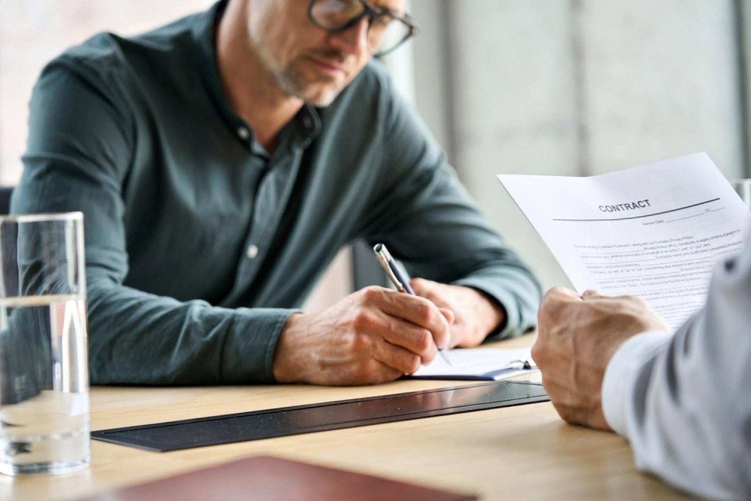 Consultant signing an HR audit compliance contract during a review meeting in the UAE